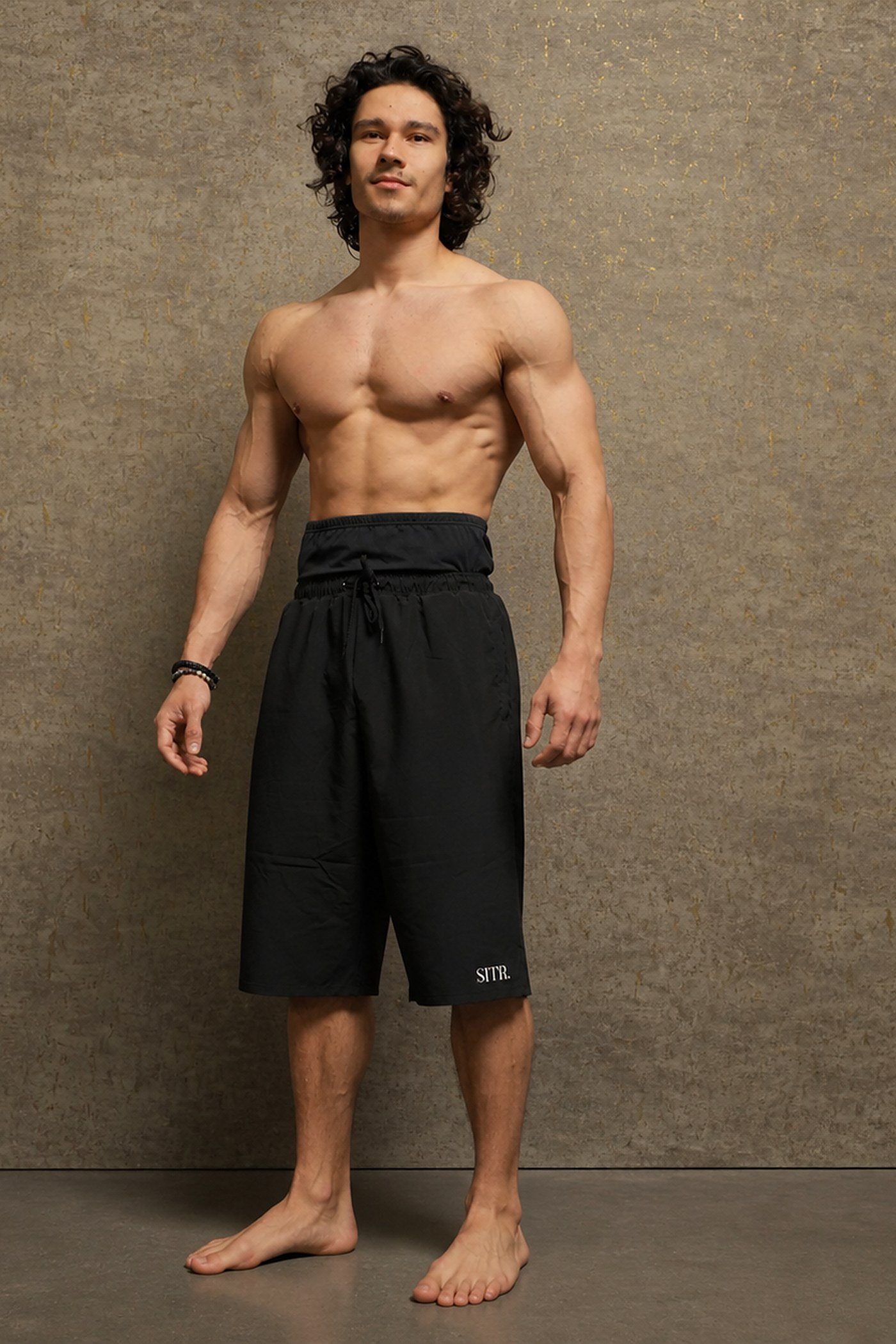 Model draagt de zwarte SITR. Long Fit Short, een islamitische sportbroek voor heren met een tailleband boven de navel en een pijp tot onder de knie